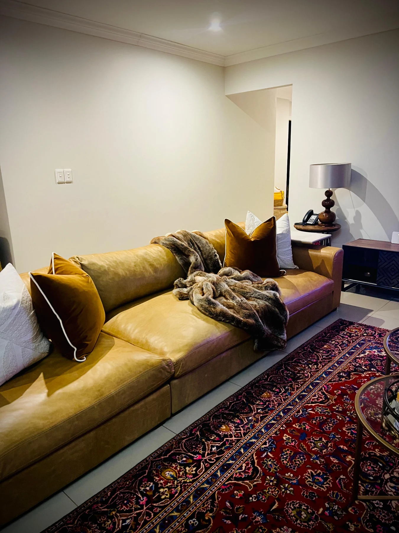 Warm residential lounge with mustard sofa, layered cushions and patterned rug