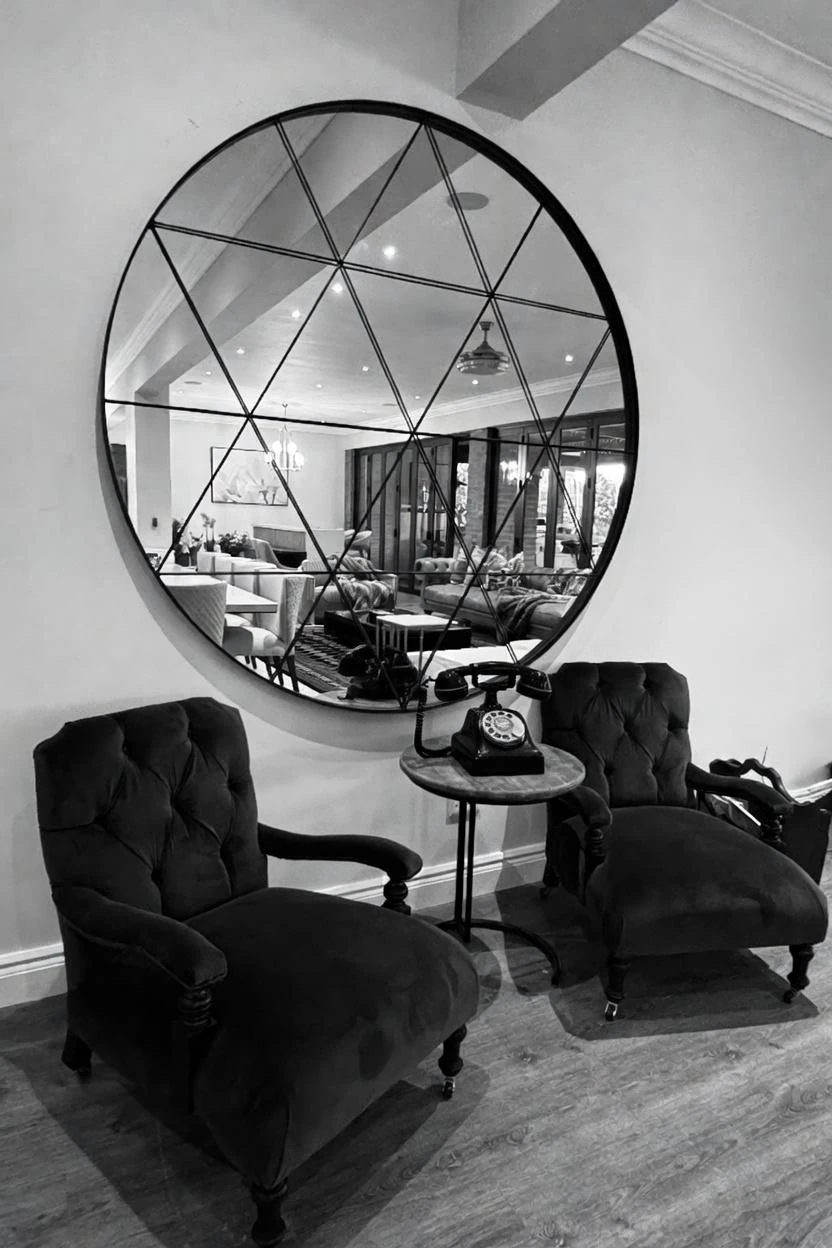 Round geometric mirror above classic lounge chairs