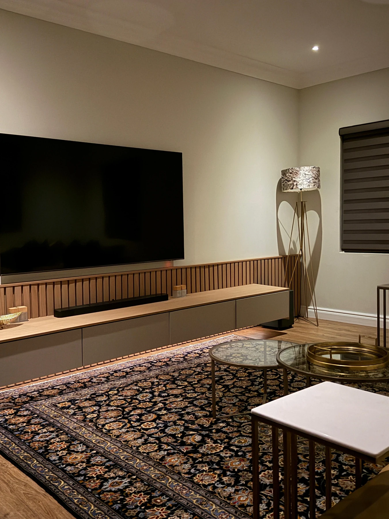 Warm residential media room with custom television wall and layered rug